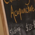 chalk board with "acupuncture" and "sliding scale" written on it