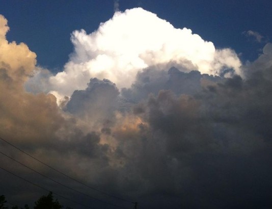 Dramatic image of a stormcloud in shades of white, grey and orange, against a dark blue sky.