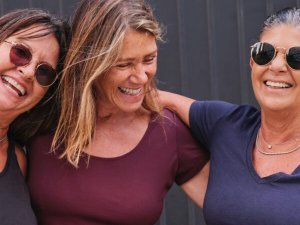 Three laughing women standing with their arms around each other
